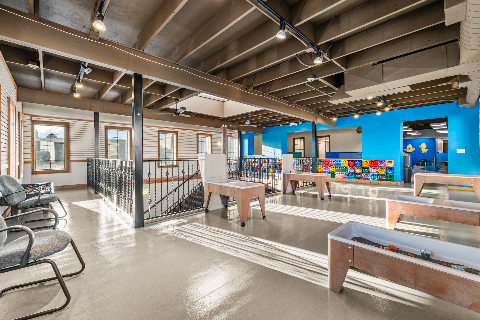 Upper level of Six Little Ducks with sensory tables and a colorful mirror wall