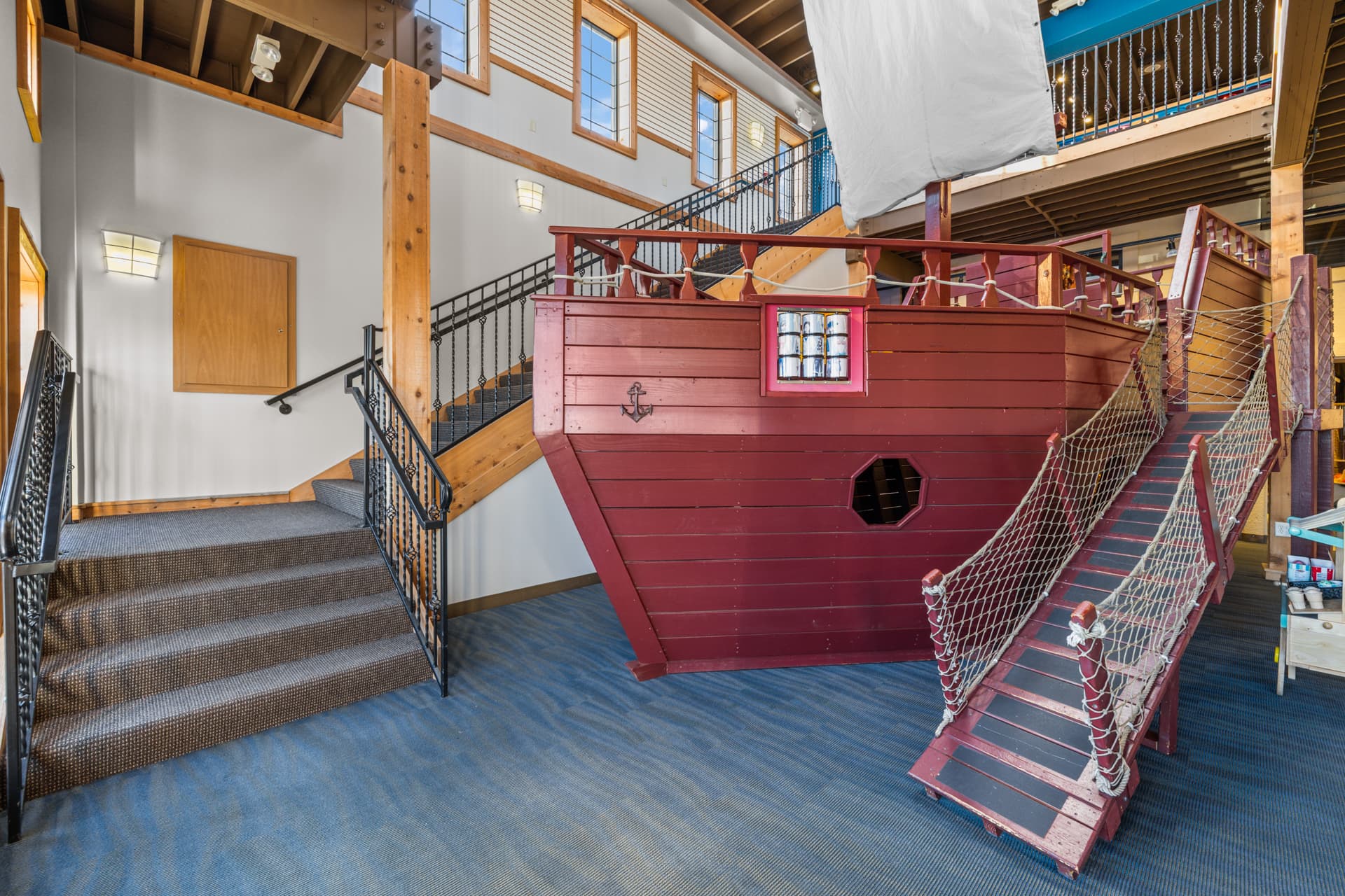 Red wooden pirate ship with an anchor and rope net gangway at Six Little Ducks indoor play space