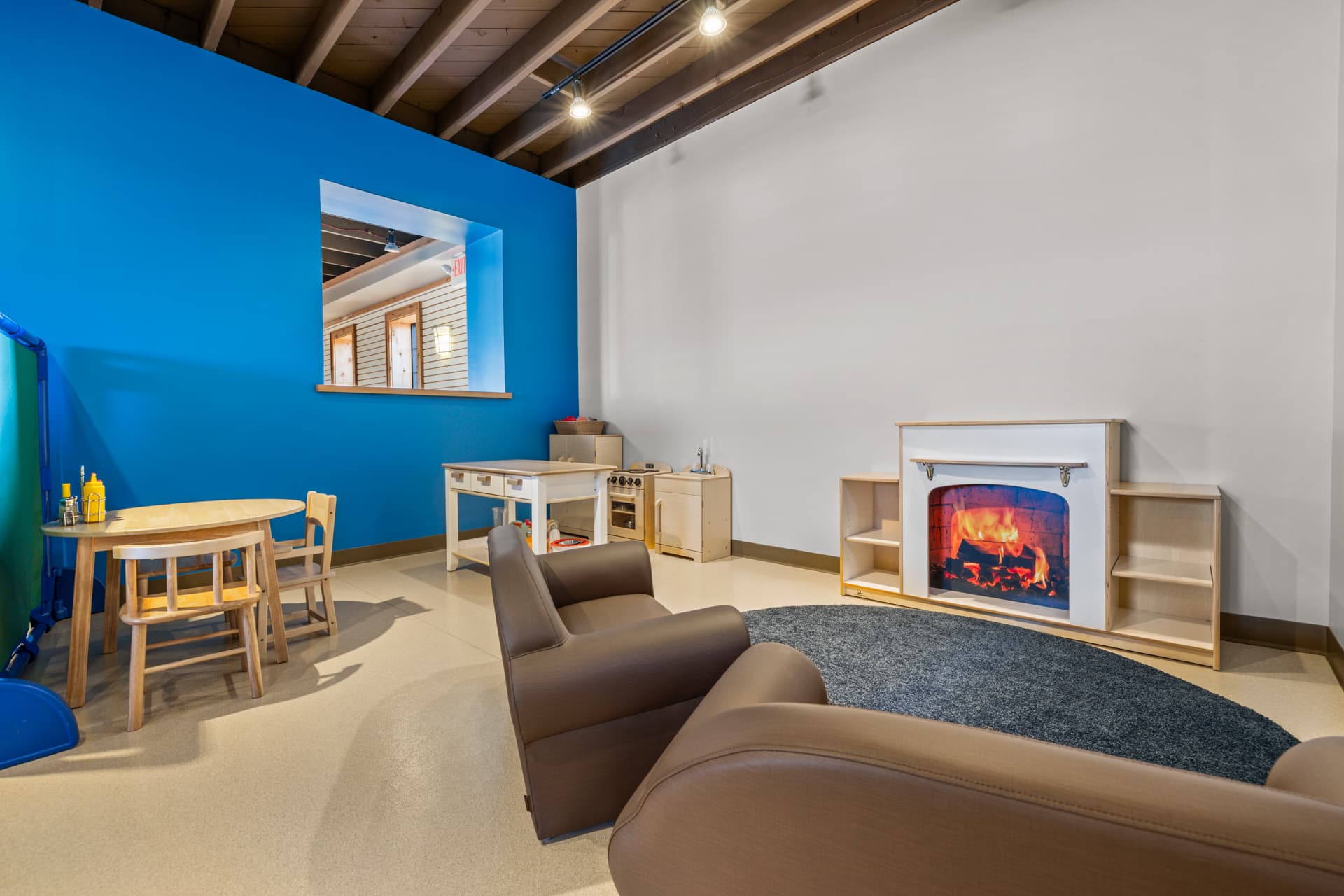 Cozy play kitchen with a pretend fireplace, kid-sized armchairs and a table at Six Little Ducks