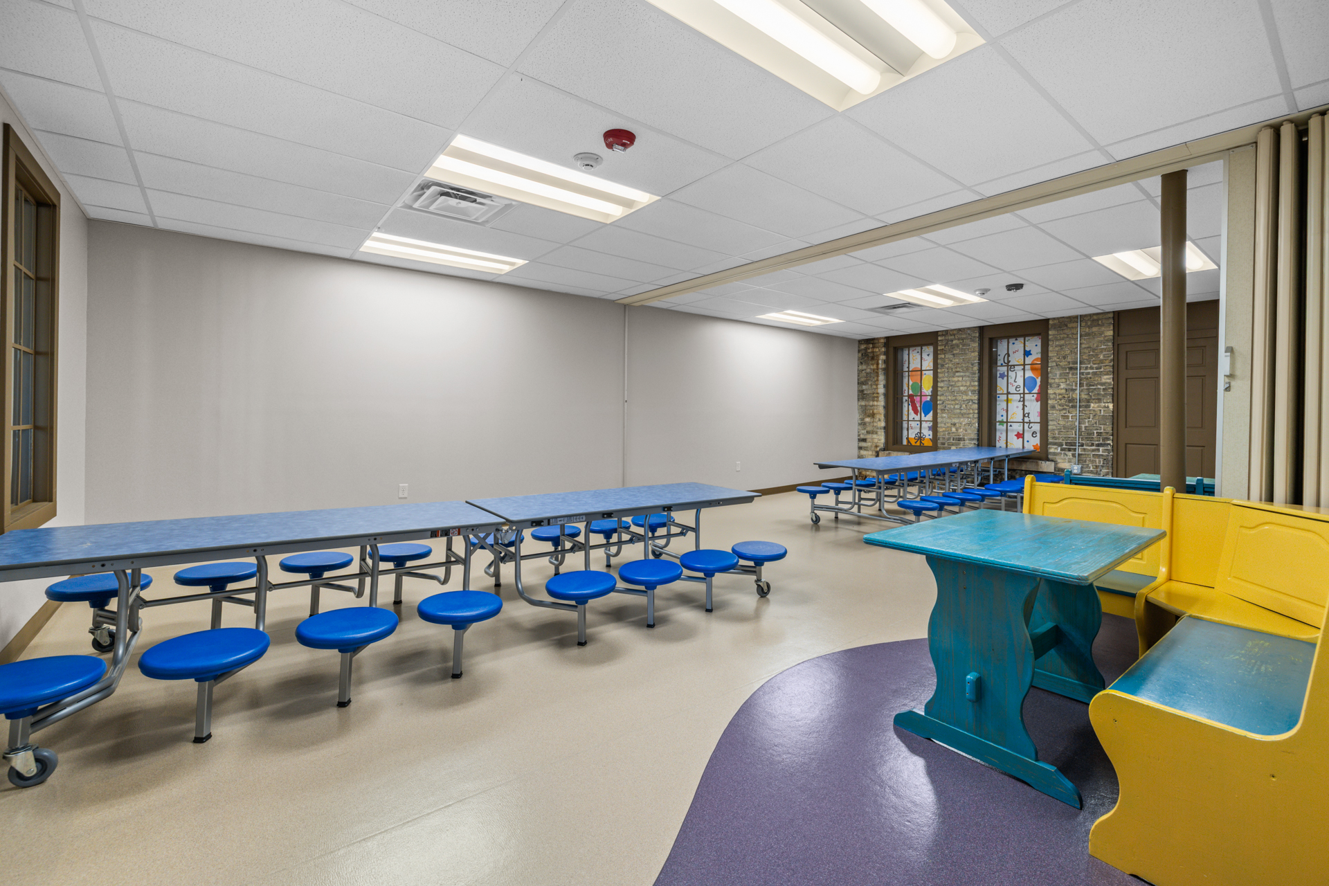 Party and dining room with long blue tables, stools and a rustic teal table with a yellow bench at Six Little Ducks